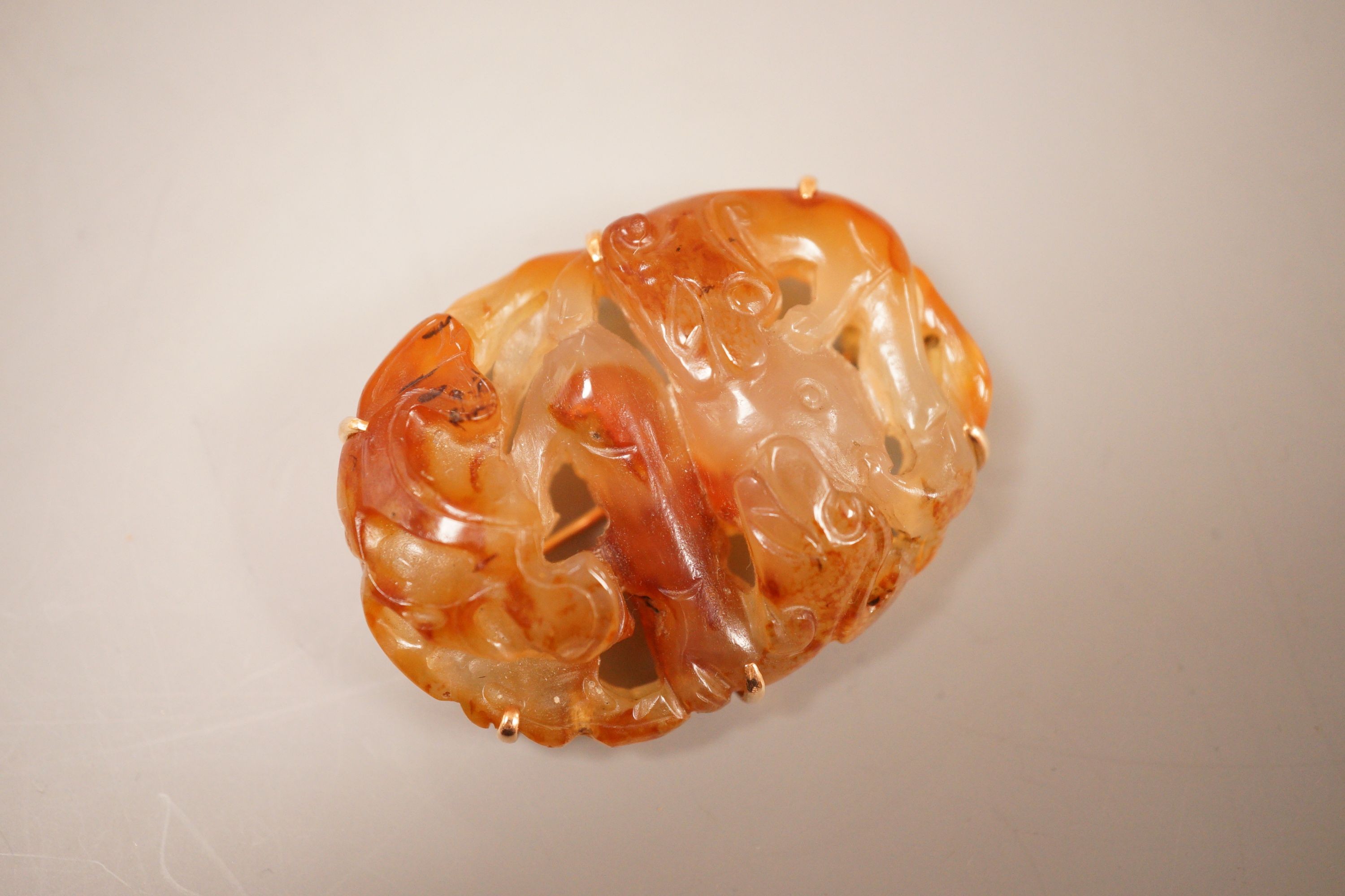 A Chinese carved agate plaque, Qing dynasty, later mounted as a brooch, 5.5cm long